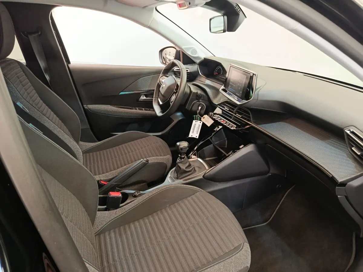Vue intérieure côté conducteur de la Peugeot 208 PureTech 100 S&S Style 2022 avec volant cuir et écran tactile.