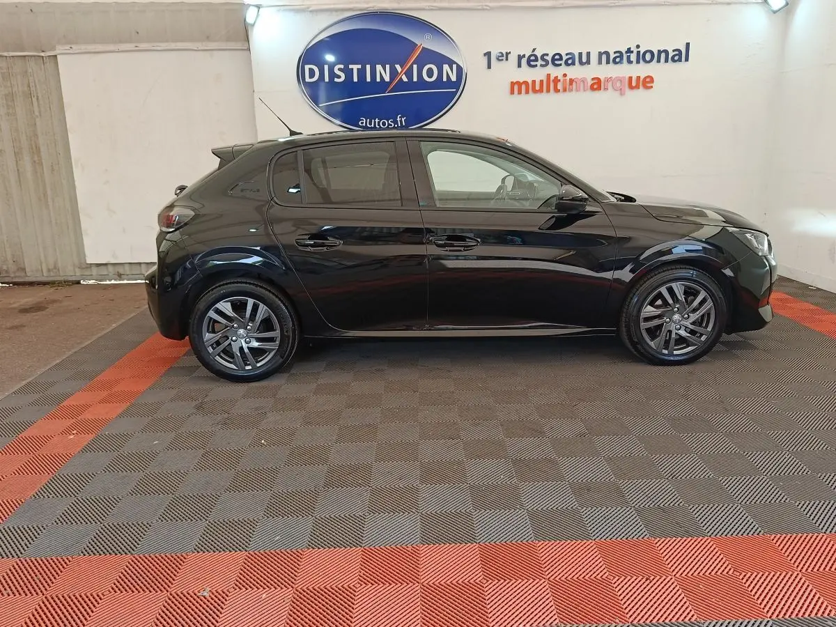 Profil côté gauche d'une Peugeot 208 PureTech 100 S&S Style noire, avec jantes alliage et vitres teintées, en intérieur showroom.