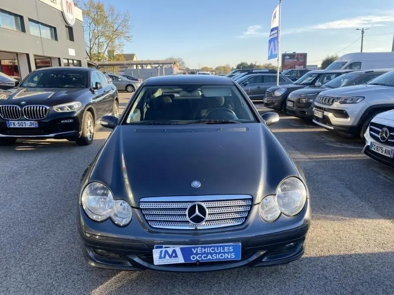 Vue avant d'une Mercedes Classe C Coupé Sport 220 CDI gris foncé métal stationnée en extérieur sur un parking.