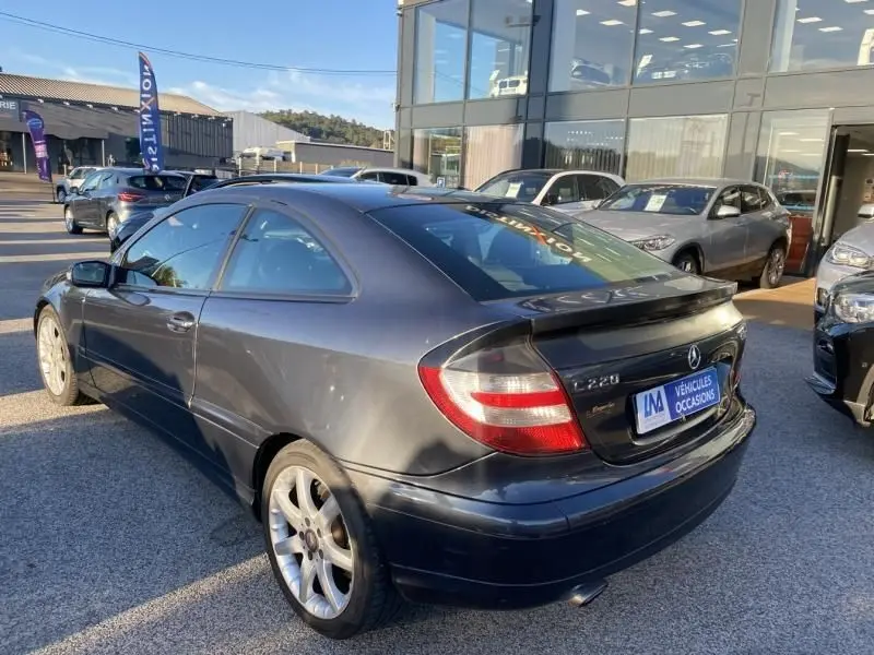 Vue 3/4 arrière droite d'une Mercedes Classe C Coupé Sport 220 CDI gris foncé métal stationnée en extérieur.