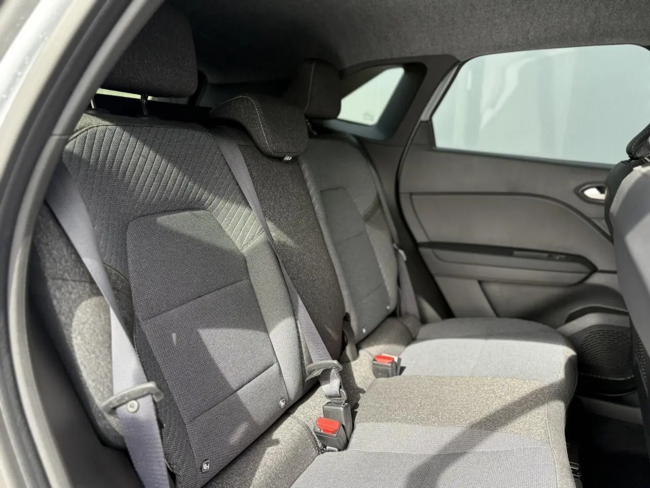 Vue intérieure côté droit sur la banquette arrière grise du Renault Symbioz E-Tech 2025 avec ceintures et appuie-têtes.