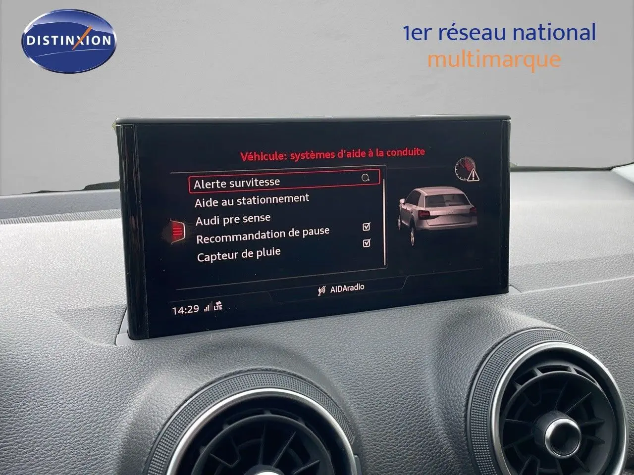 Écran central affichant les aides à la conduite dans l'habitacle d'un Audi Q2 noir mito metal, vue de face.