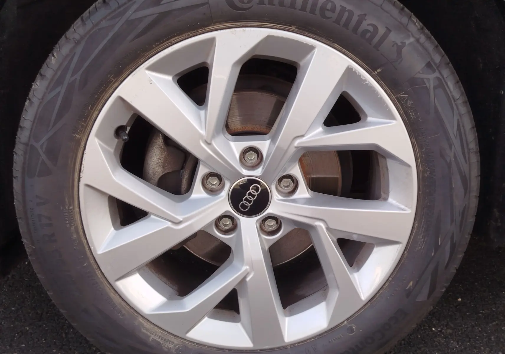 Gros plan sur la jante alliage argentée 17 pouces avec logo Audi, montée sur pneu Continental d’un Audi Q2 noir.