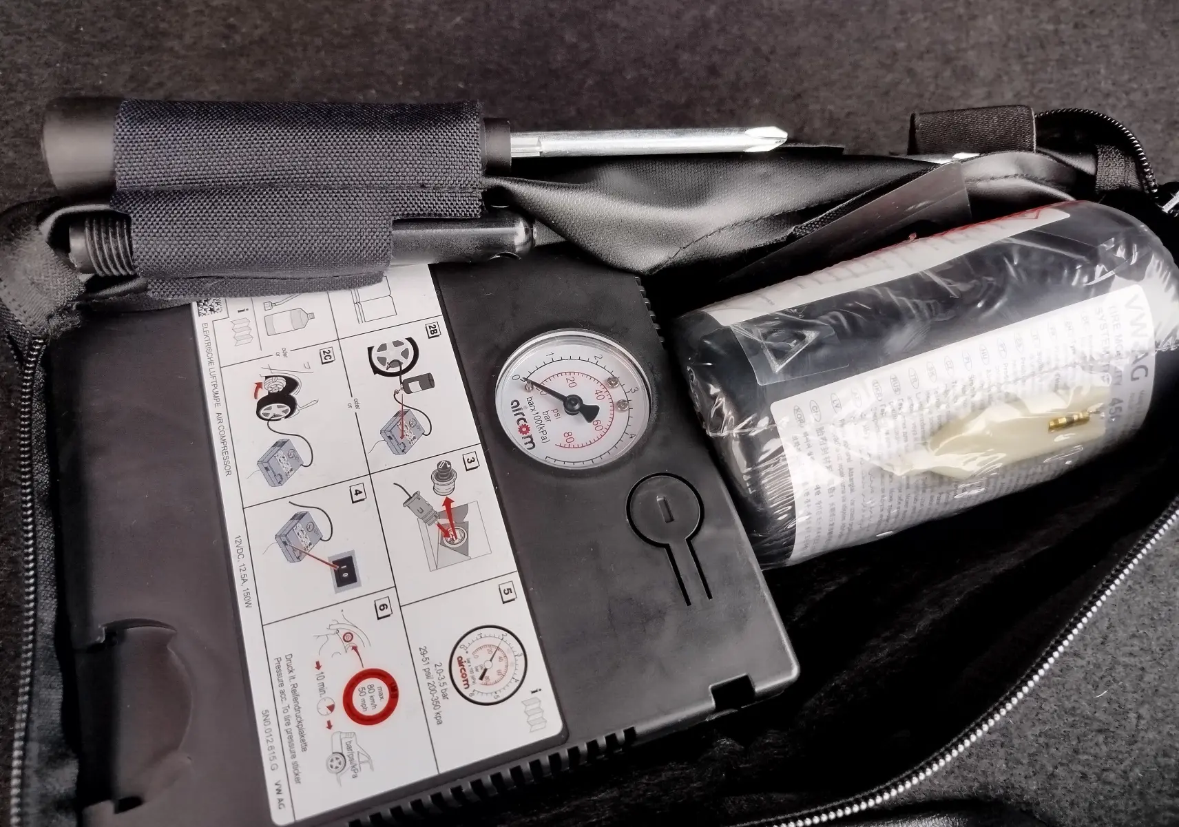 Image montrant un kit de réparation pneus noir dans le coffre d’un Audi Q2 35 TFSI 2023 noir mito metal.