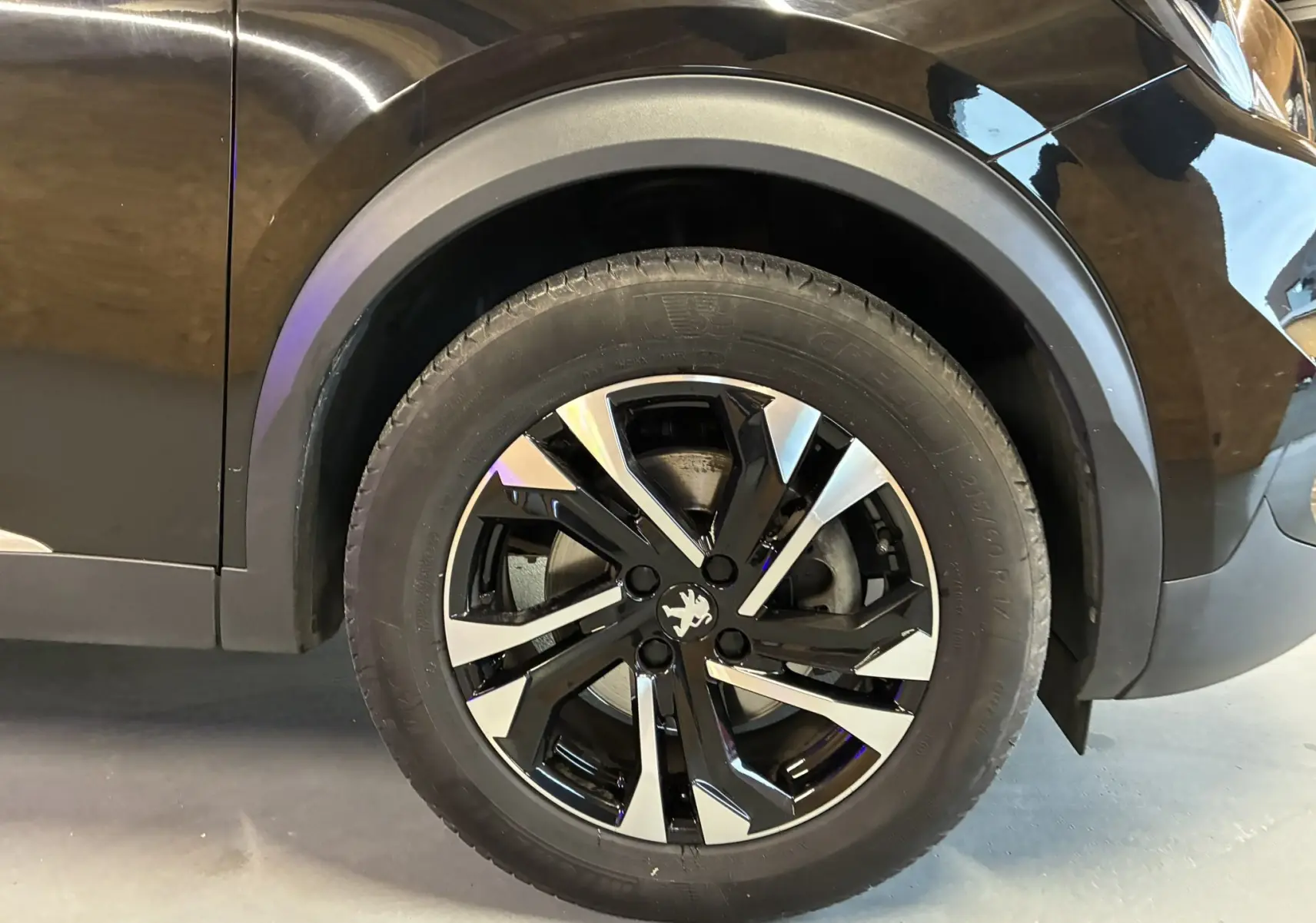 Gros plan sur la roue avant gauche noire du Peugeot 2008 1.5 BlueHDi 130 GT Line avec jante bi-ton distinctive.