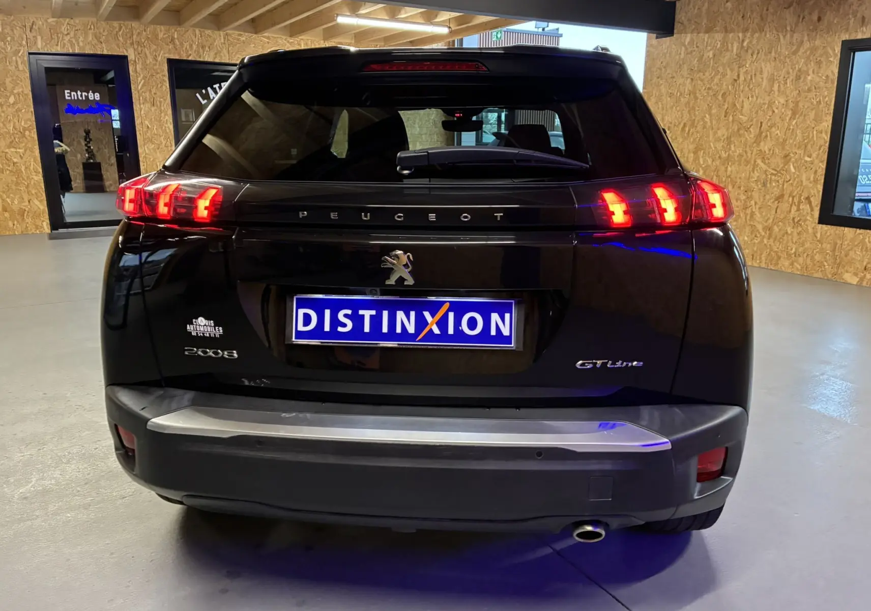 Vue arrière d'un Peugeot 2008 GT Line noir avec feux LED allumés et plaque d'immatriculation Distinxion visible en intérieur.