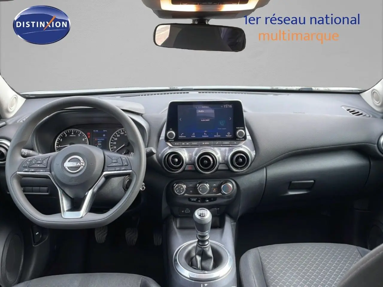 Vue intérieure frontale du tableau de bord du Nissan Juke noir perle 2023 avec volant multifonction et écran tactile central.