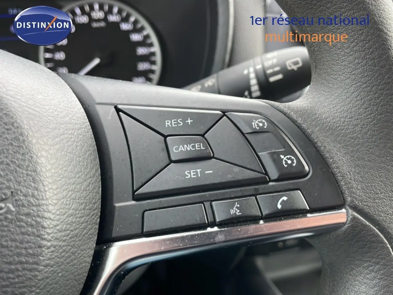 Gros plan sur les commandes au volant noir du Nissan Juke 2023, mettant en valeur les boutons de régulateur de vitesse.