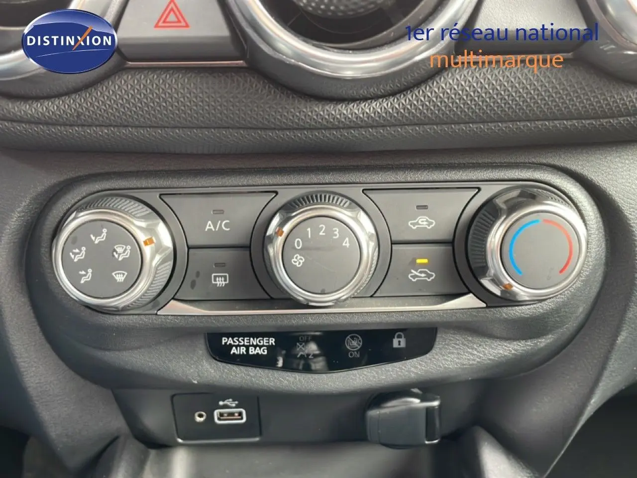 Vue rapprochée de la console centrale du Nissan Juke noir perle 2023, montrant les commandes de climatisation et connectiques USB.
