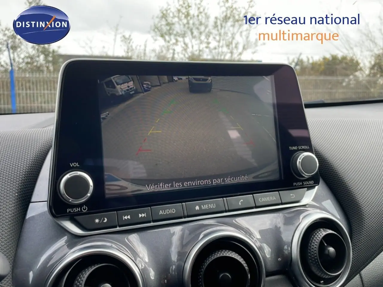 Écran central affichant la caméra de recul du Nissan Juke 2023, intérieur gris noir avec commandes audio et climatisation.