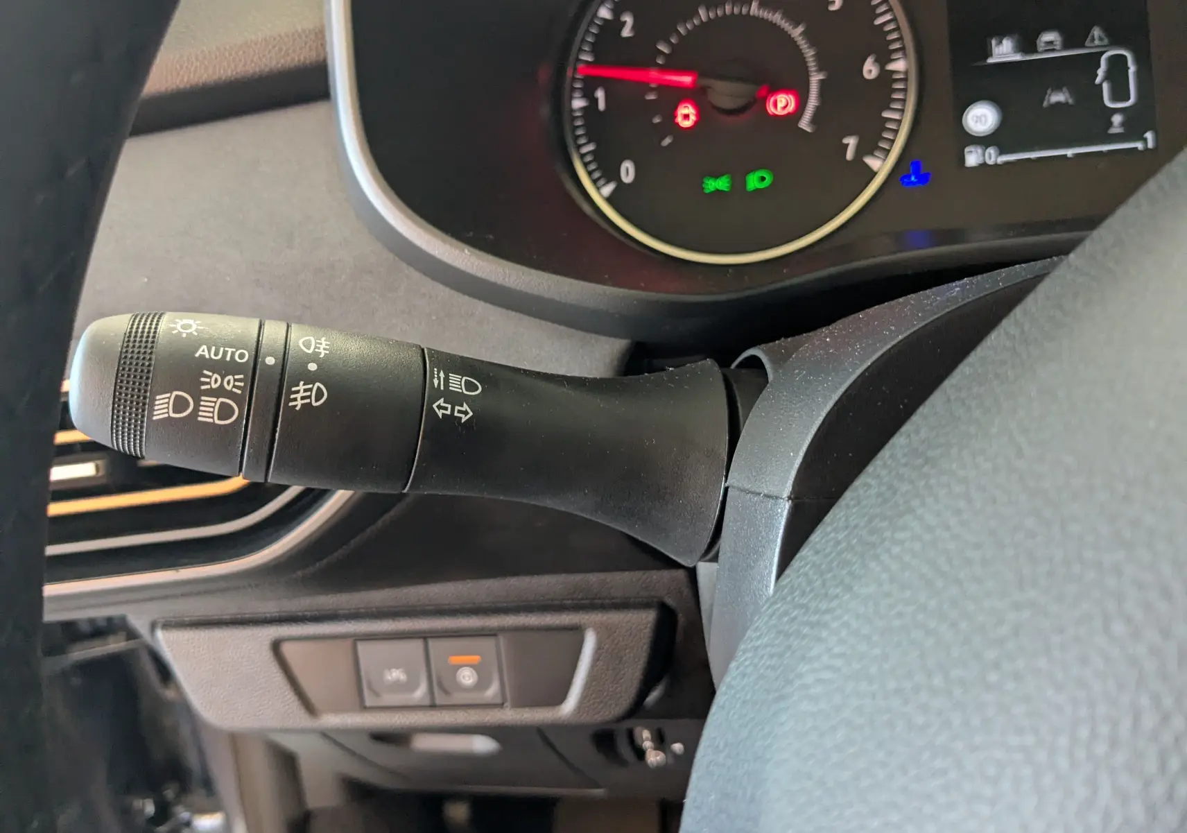 Gros plan sur la manette de commande des phares et clignotants du tableau de bord du Dacia Jogger gris schiste.