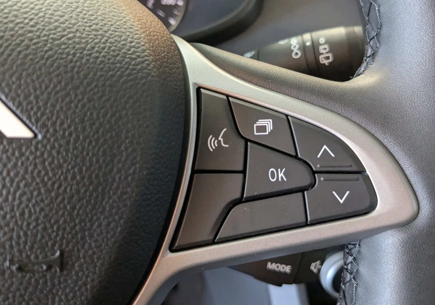Gros plan sur les commandes multifonctions à droite du volant noir du Dacia Jogger 2026, boutons noirs avec marquages blancs.