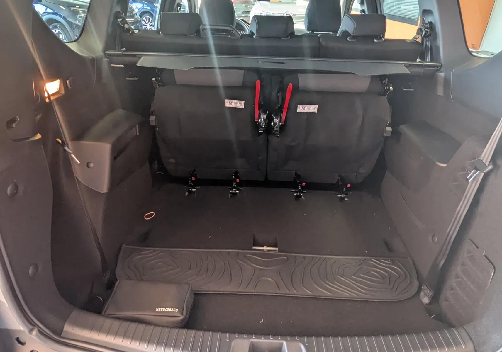 Coffre ouvert du Dacia Jogger gris schiste métal, vue arrière montrant la troisième rangée de sièges rabattue et l'espace de chargement.