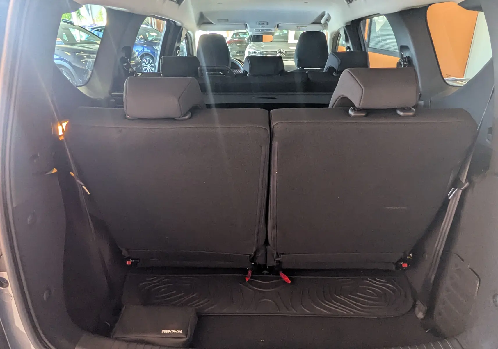 Vue arrière intérieure du Dacia Jogger gris schiste, montrant la troisième rangée de sièges relevée et l'habitacle en arrière-plan.