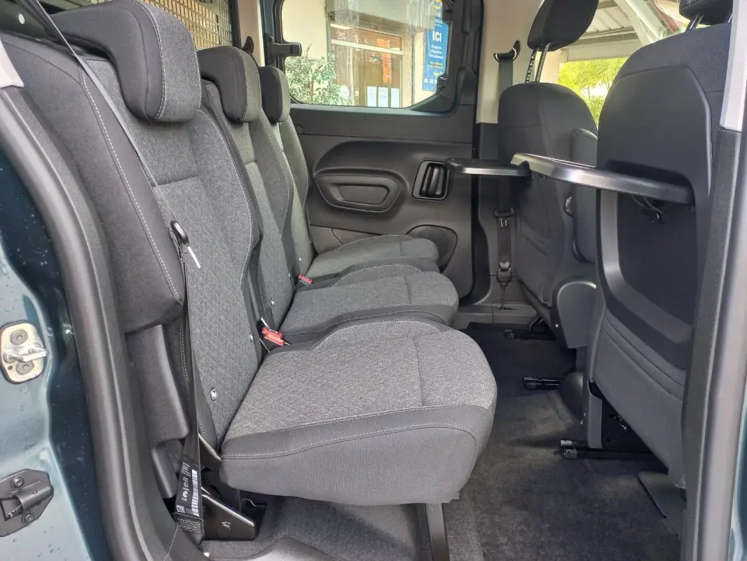 Vue intérieure côté gauche des sièges arrière gris du Opel Combo Life Elegance M 2025, avec tablette rabattable sur le dossier avant.