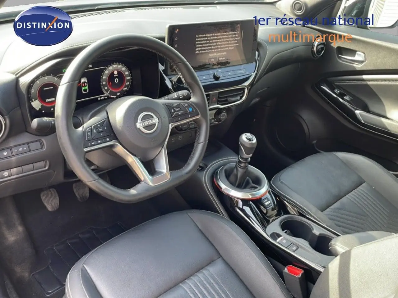 Vue intérieure côté conducteur du Nissan Juke 2025 noir Kuro Metal, volant cuir, boîte manuelle et écran tactile central.
