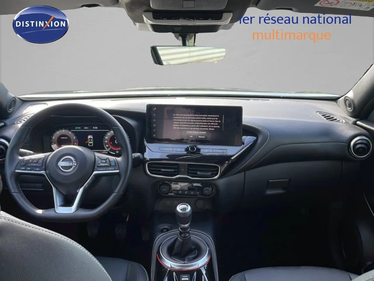 Vue intérieure avant du Nissan Juke 2025 noir Kuro Metal, tableau de bord moderne avec écran central et boîte manuelle.