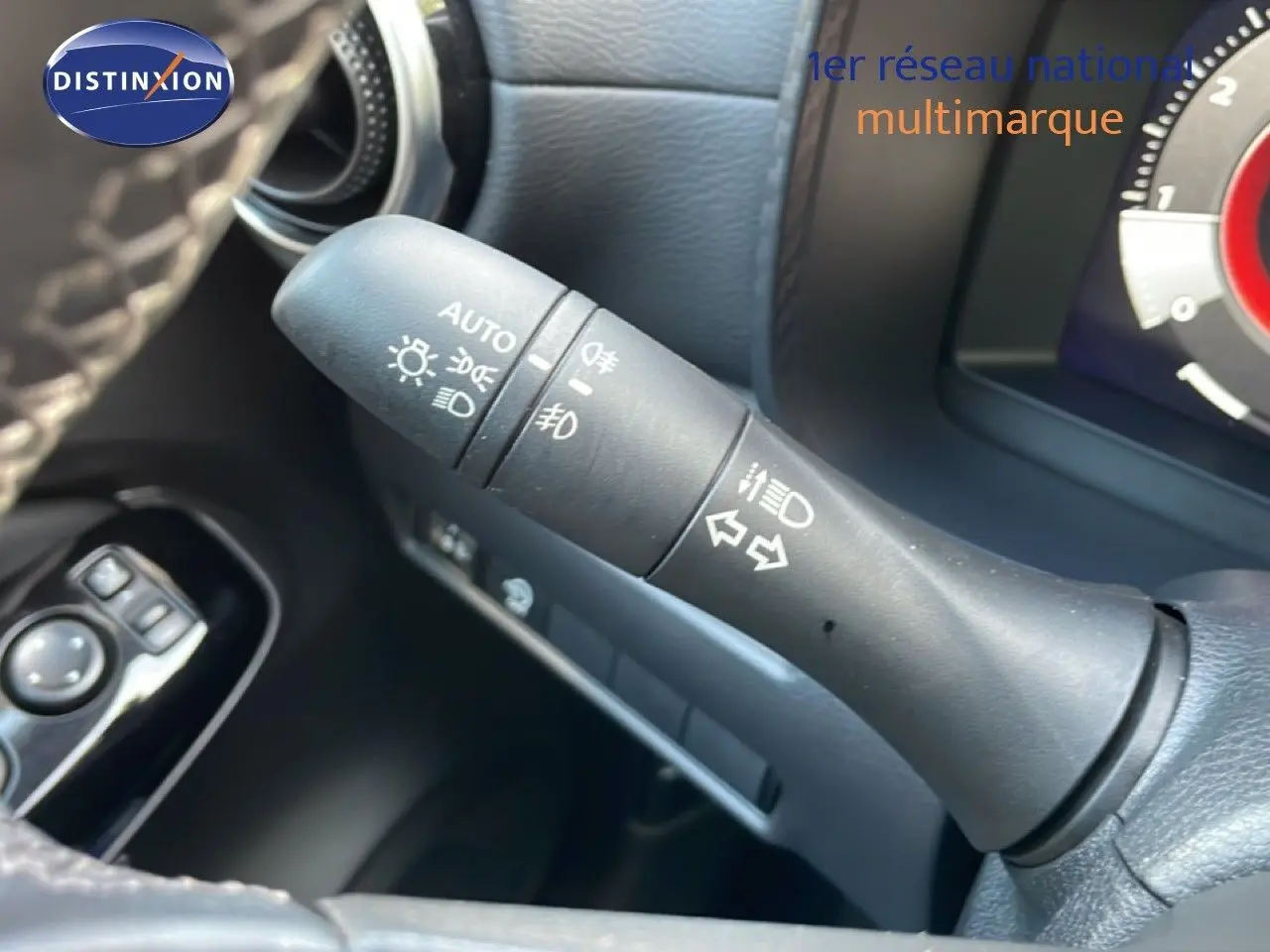 Gros plan sur la commande des feux et clignotants à gauche du volant dans l’habitacle noir du Nissan Juke 2025.