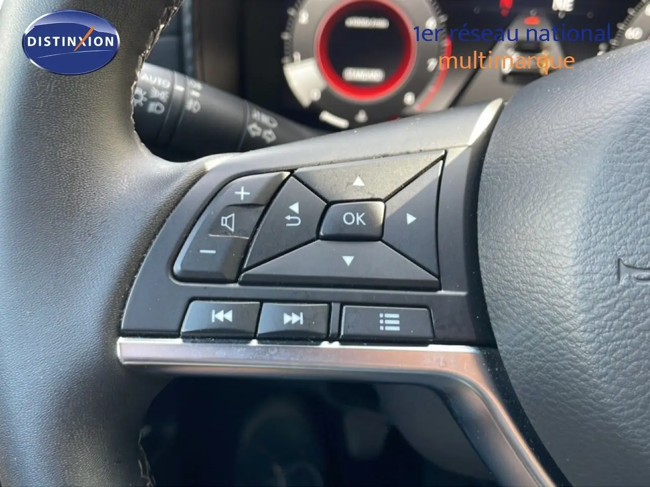 Gros plan sur les commandes au volant côté gauche du Nissan Juke 2025 noir Kuro Metal, avec tableau de bord partiellement visible.
