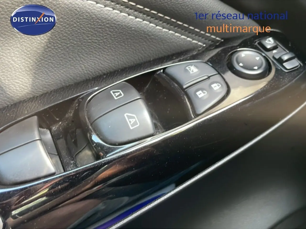 Gros plan sur les commandes de lève-vitres et rétroviseurs côté conducteur du Nissan Juke noir Kuro Metal 2025.