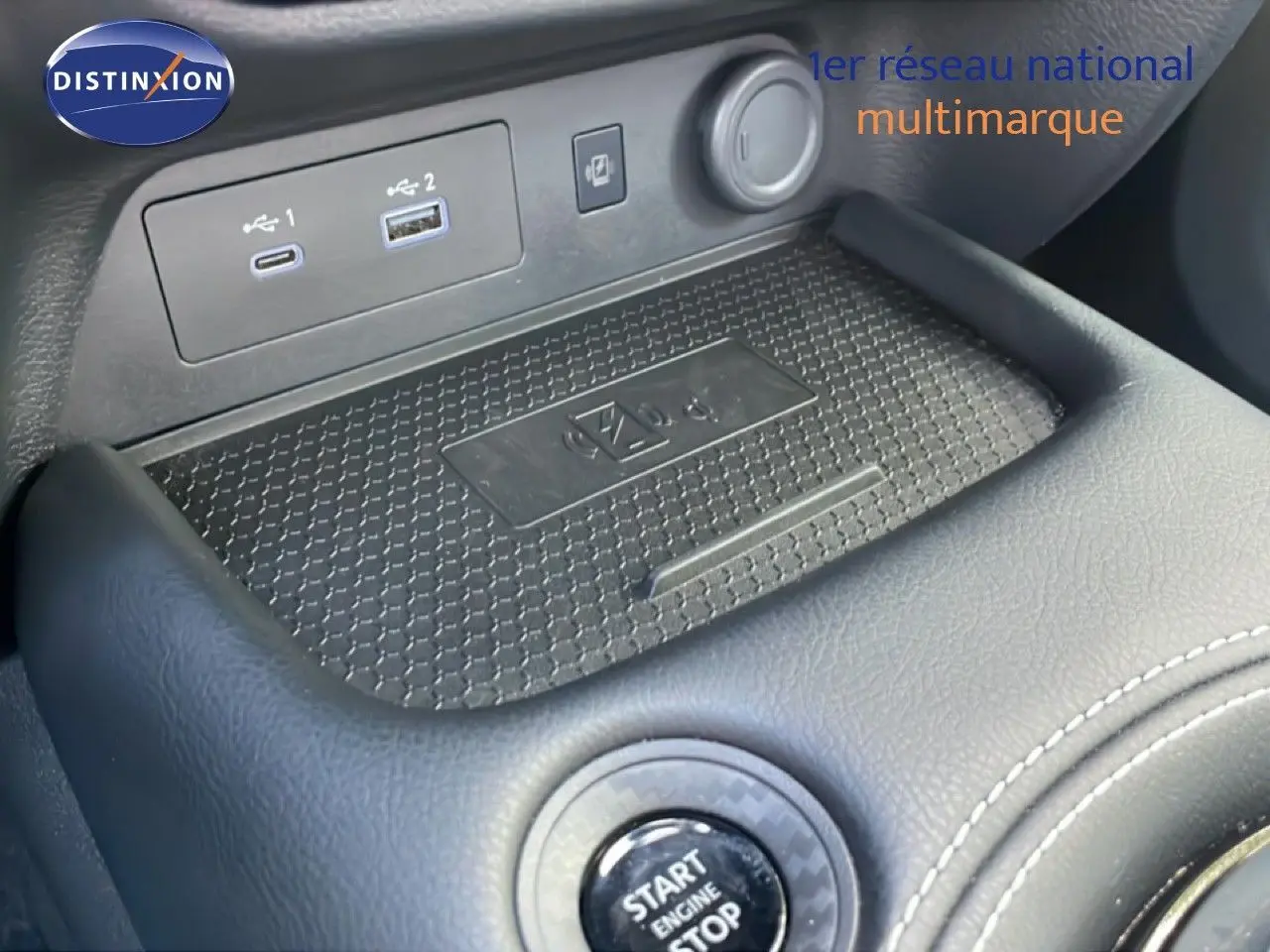 Gros plan sur la console centrale du Nissan Juke 2025 noir, montrant le bouton start/stop et les ports USB.