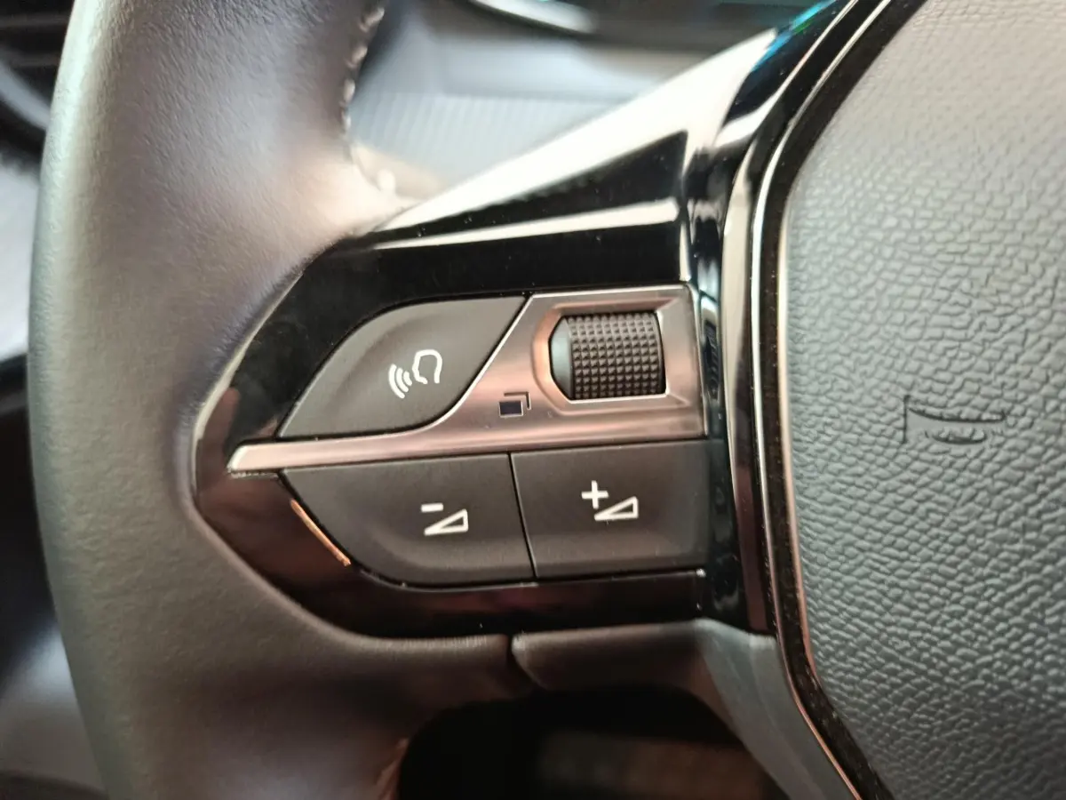 Gros plan sur les commandes multifonctions du volant cuir noir du Peugeot E-2008 électrique Active Pack 2023.