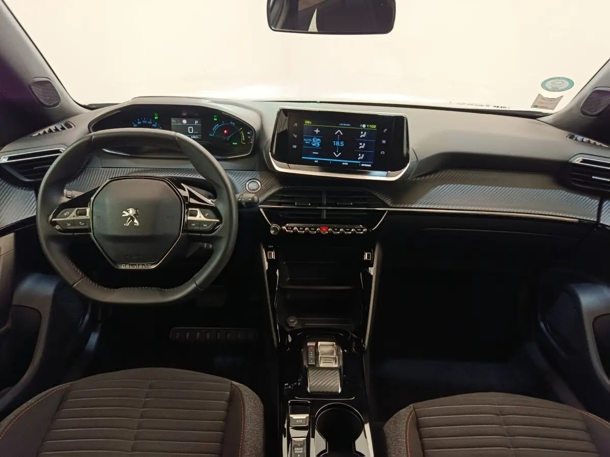 Vue intérieure frontale du tableau de bord et volant cuir noir du Peugeot E-2008 électrique gris clair, avec écran tactile central.