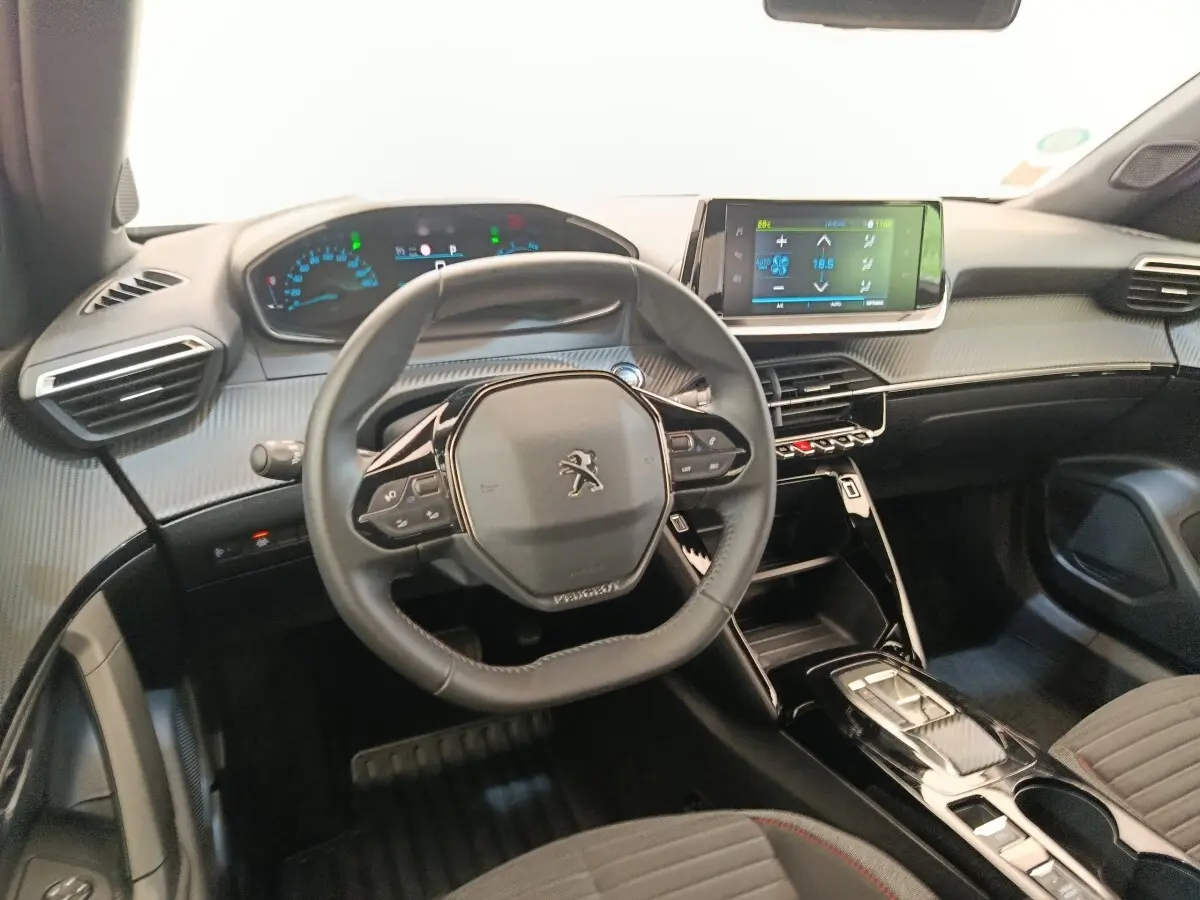Intérieur du Peugeot E-2008 électrique 2023, vue du poste de conduite avec volant cuir multifonctions et écran tactile central.