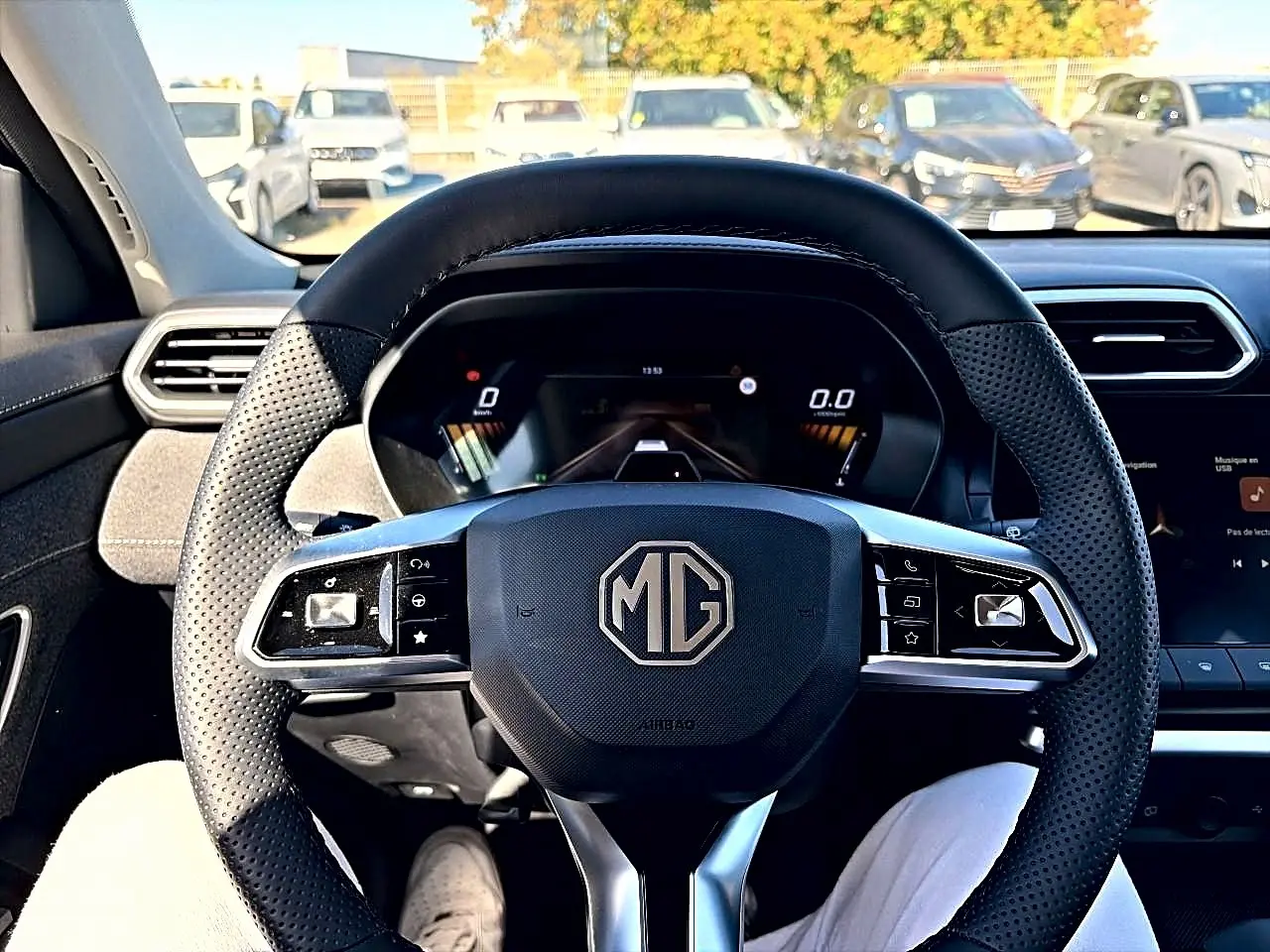 Vue centrée du volant perforé noir du MG ZS 1.5 hybrid 197 avec tableau de bord numérique en arrière-plan.