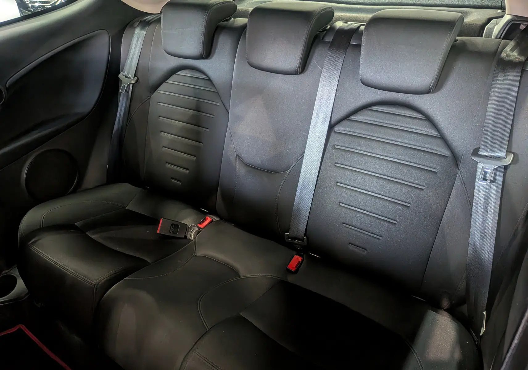 Banquette arrière en tissu noir de l'Alfa Romeo MiTo 2018, vue intérieure montrant les ceintures de sécurité et appuie-têtes.