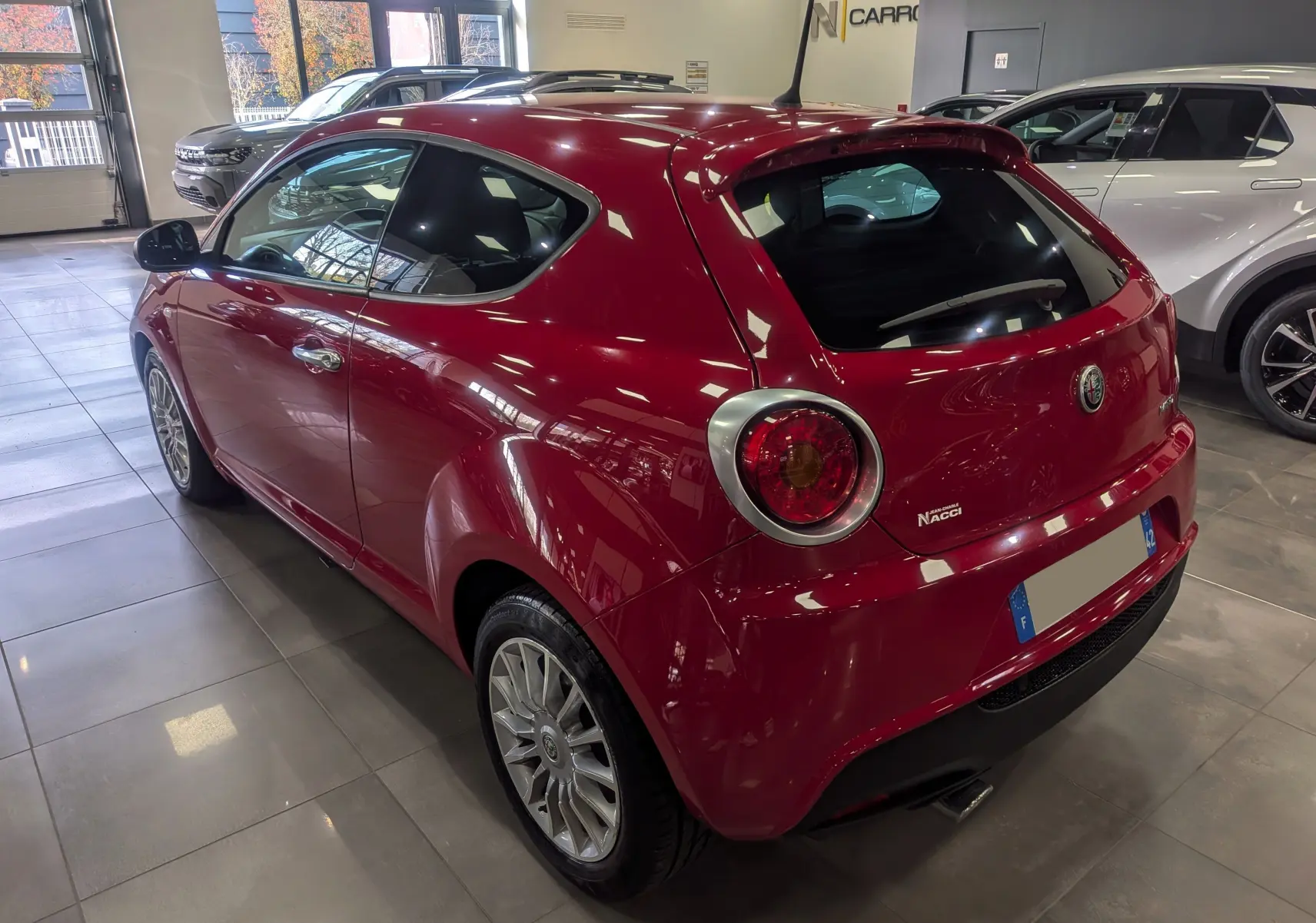 Vue 3/4 arrière droite d'une Alfa Romeo MiTo rouge Alfa 2018, avec feux ronds caractéristiques et jantes alliage.