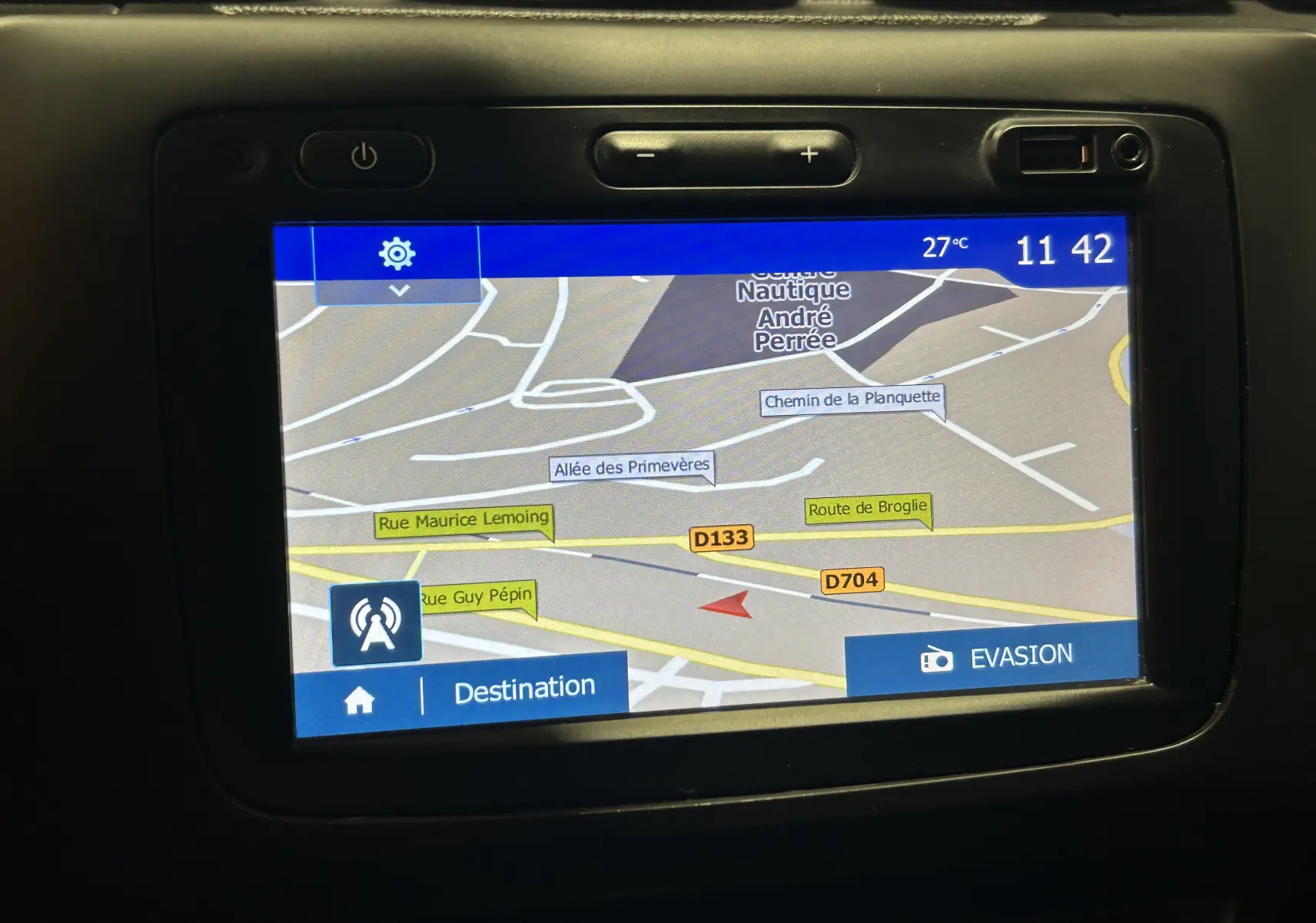 Écran GPS intégré du Dacia Duster noir, affichant une carte routière avec plusieurs noms de rues et options visibles.