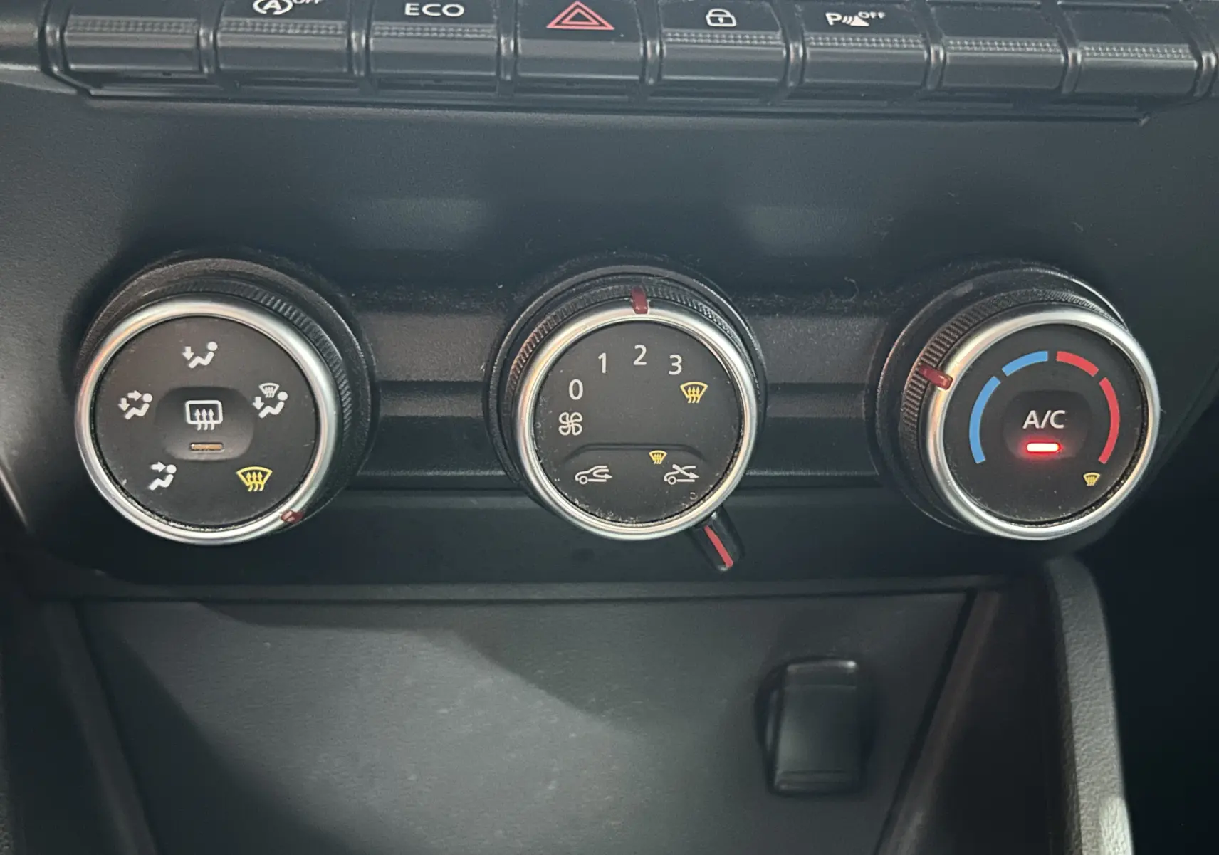 Gros plan sur les commandes de climatisation manuelle du tableau de bord noir du Dacia Duster 2018.