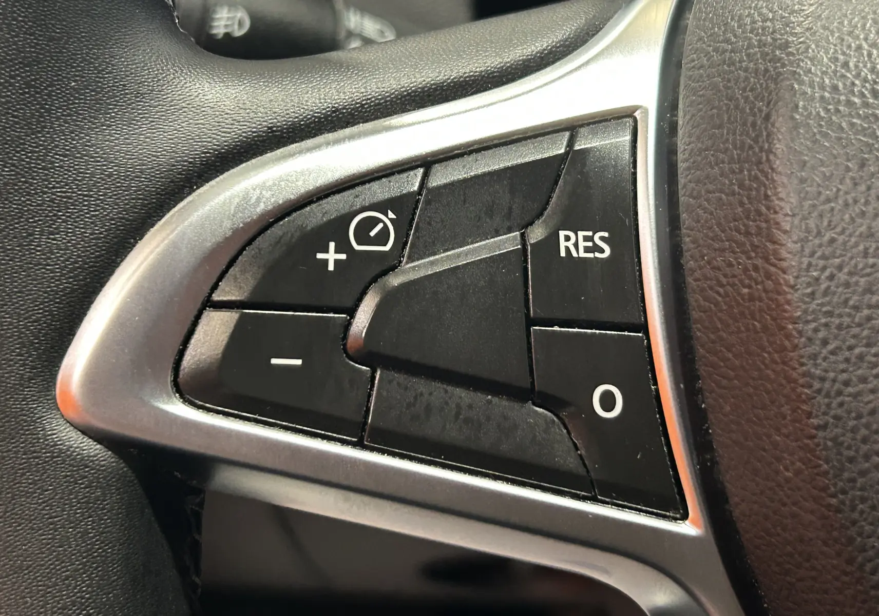 Gros plan sur les commandes noires du régulateur de vitesse au volant du Dacia Duster noir, finition Prestige 2018.