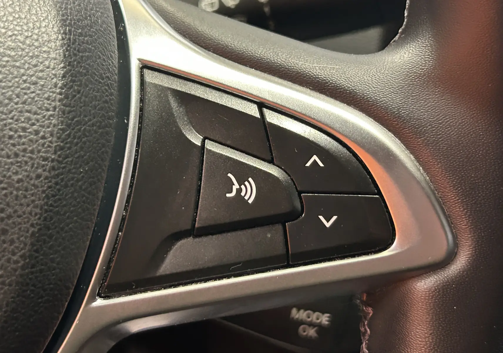 Gros plan sur les commandes noires du volant du Dacia Duster 2018, avec contour argenté et boutons de volume.