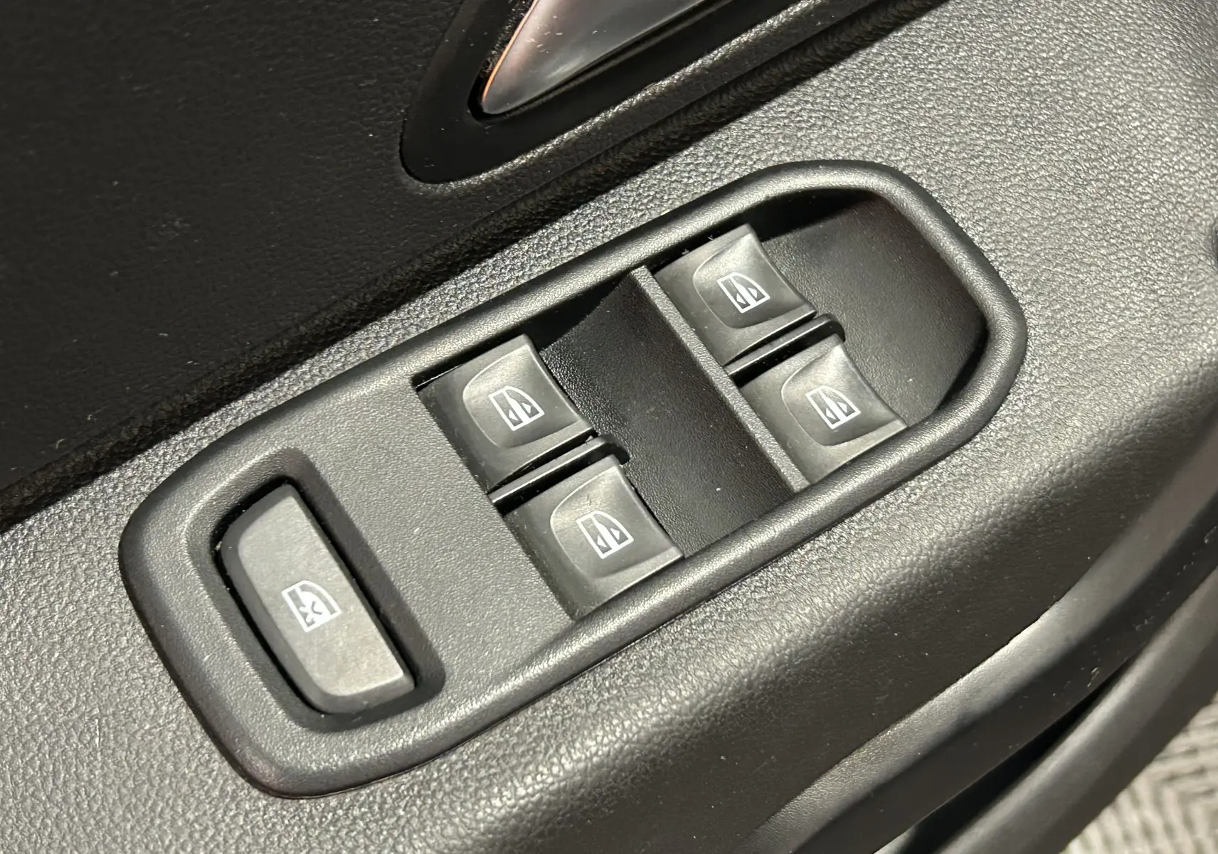 Gros plan sur les commandes des vitres électriques côté conducteur du Dacia Duster noir, version Prestige 2018.