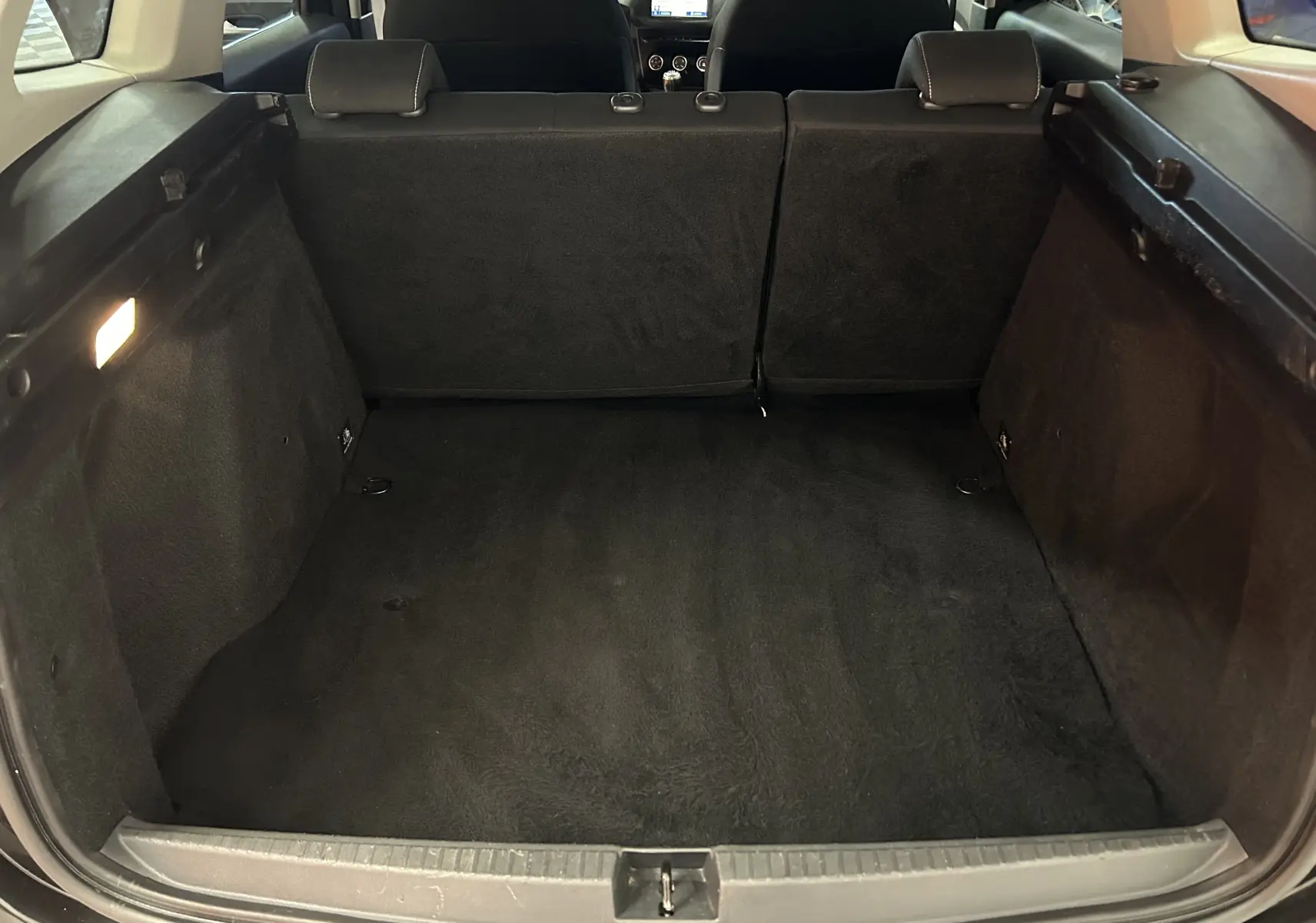 Vue depuis l'arrière du coffre noir du Dacia Duster 2018, montrant l'espace de chargement et les sièges arrière rabattus.