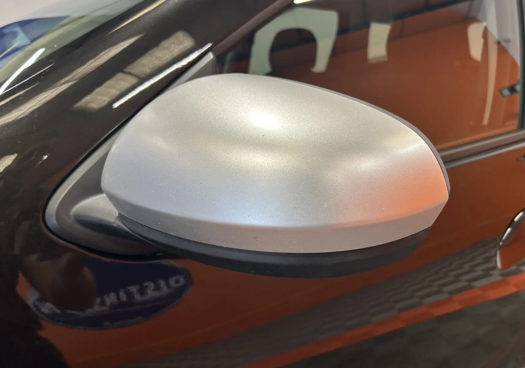 Rétroviseur extérieur argenté côté gauche sur Dacia Duster noir, vue rapprochée en léger angle.
