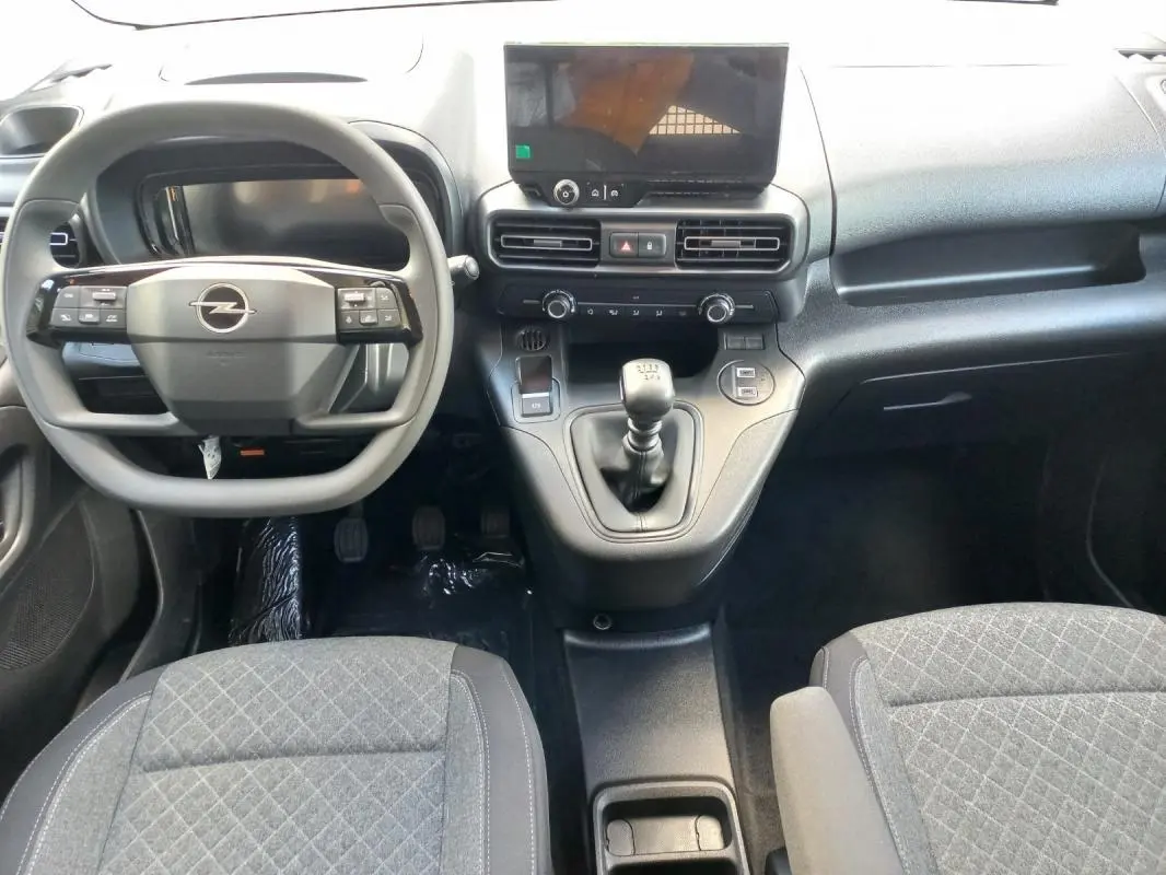 Vue intérieure avant de l’Opel Combo Life 2025, tableau de bord noir avec volant multifonction et levier de vitesse manuel.
