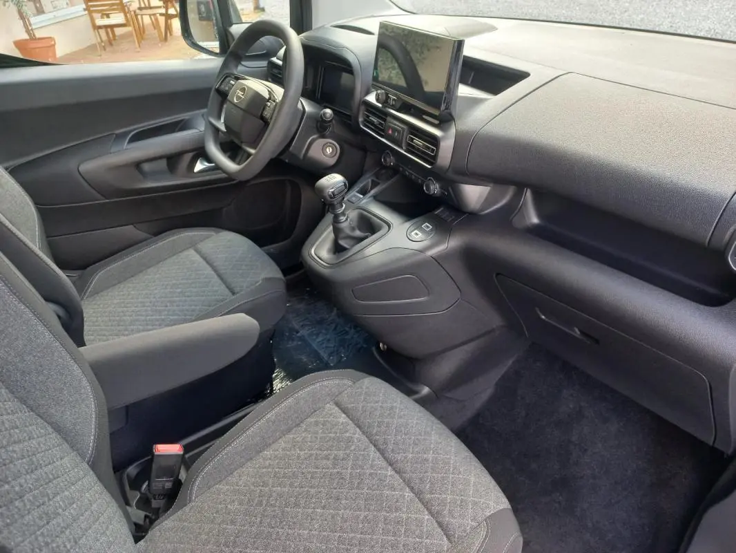 Vue intérieure côté conducteur de l’Opel Combo Life 2025, montrant le tableau de bord noir et les sièges gris tissu.