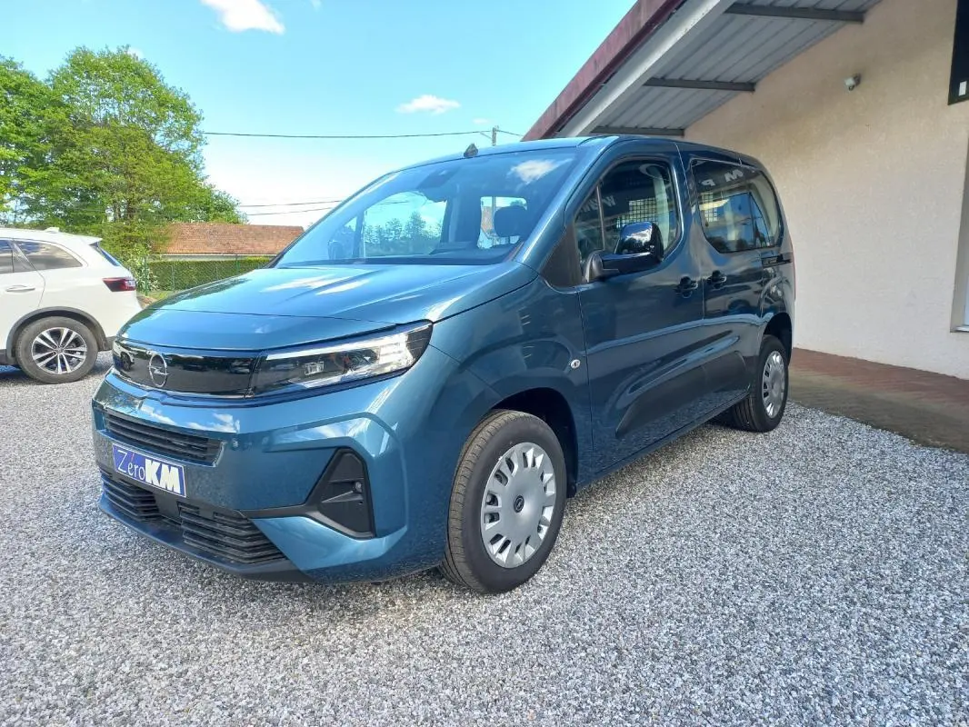 Opel Combo Life bleu en vue 3/4 avant droit, avec calandre noire et jantes acier argentées sur gravier.