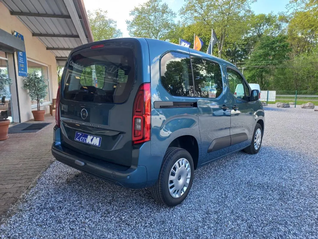 Opel Combo Life bleu en 3/4 arrière droit, avec vitres teintées et porte latérale coulissante visible.