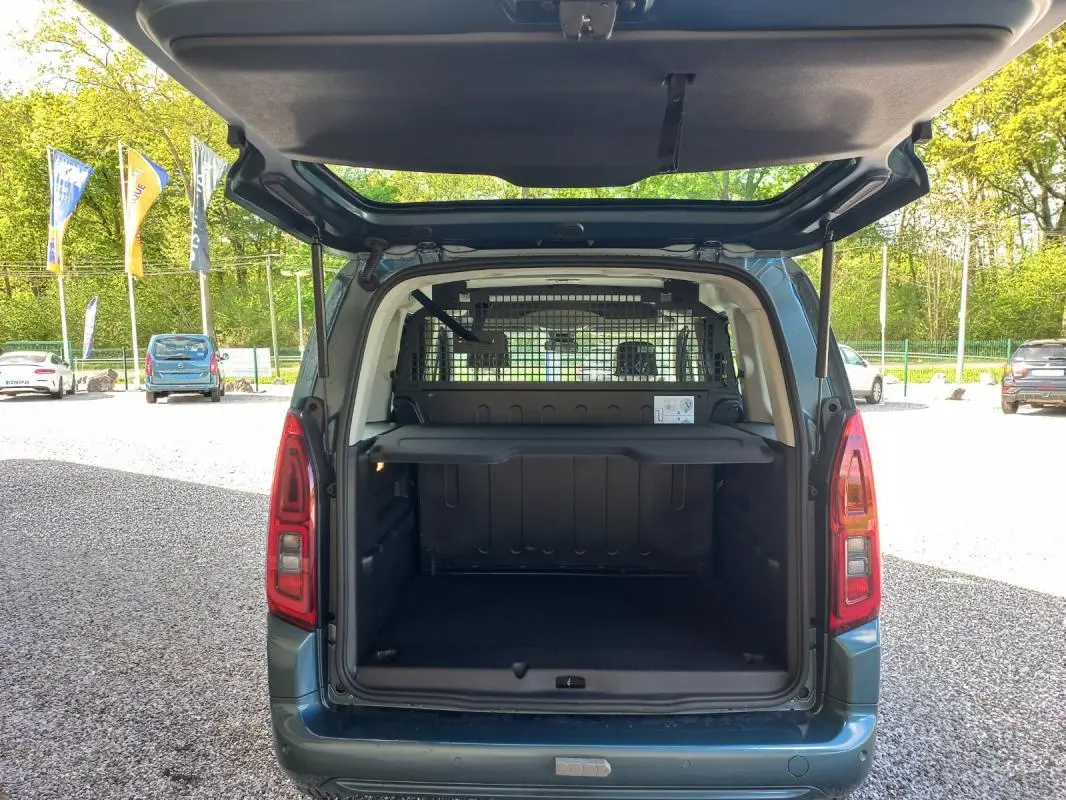 Vue arrière ouverte du fourgon Opel Combo Life M bleu 2025, montrant l'espace de chargement avec séparation grillagée.