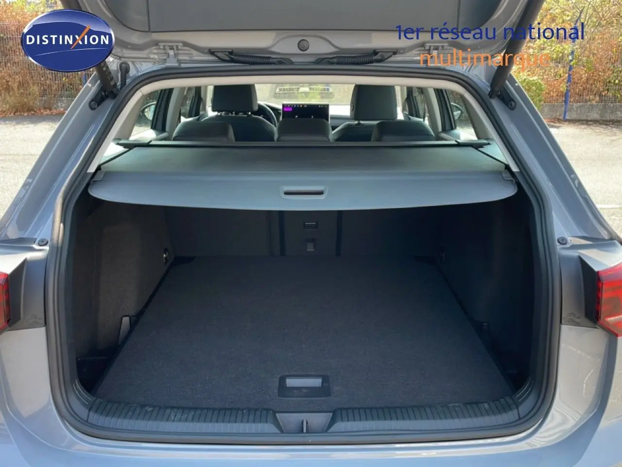 Coffre ouvert d’une Volkswagen Golf SW VIII gris lunaire métal, vue arrière montrant l’espace de chargement et l’intérieur des sièges.