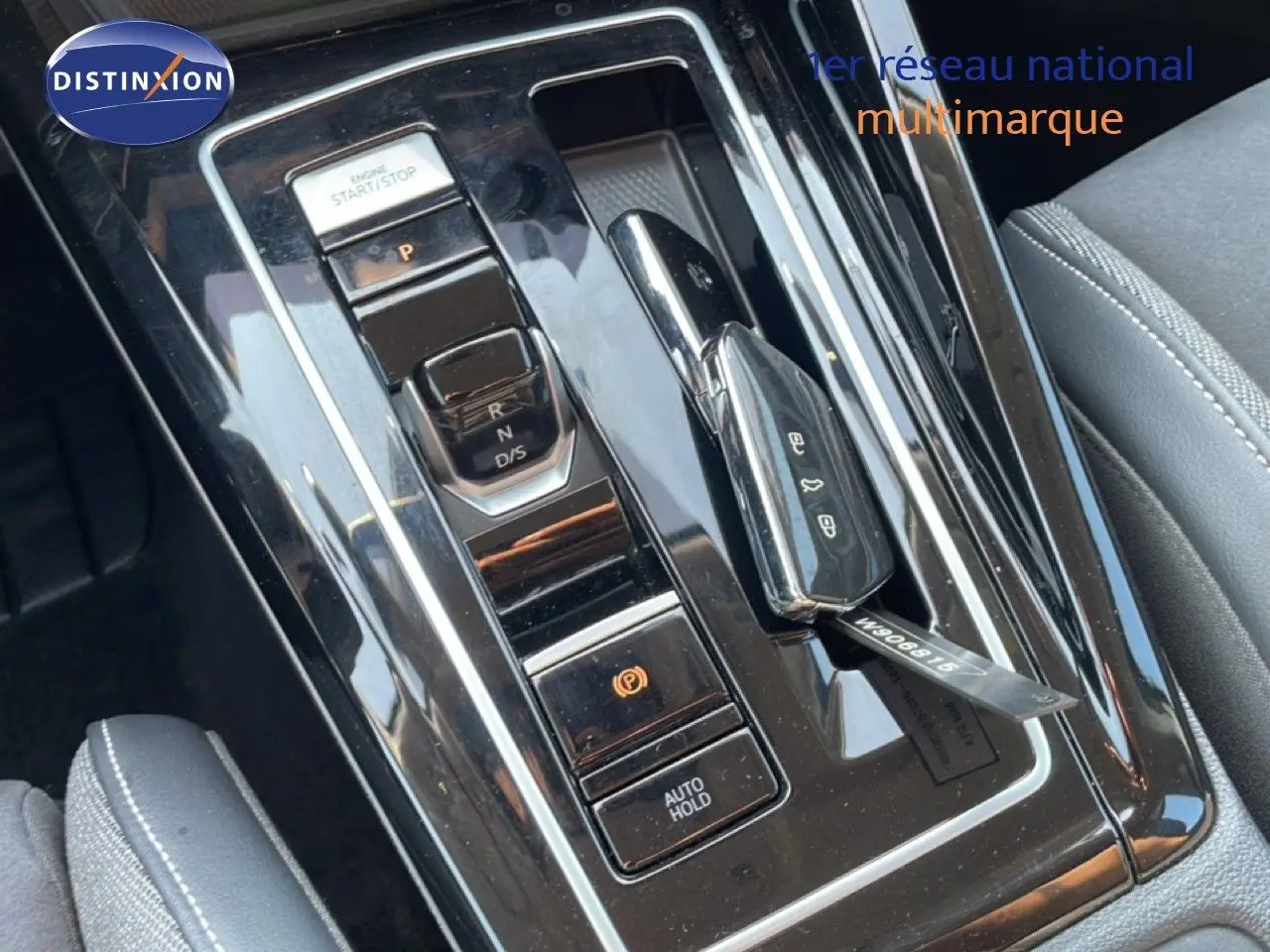 Vue rapprochée de la console centrale noire brillante avec levier de vitesses et bouton start/stop d’une Volkswagen Golf SW gris lunaire.