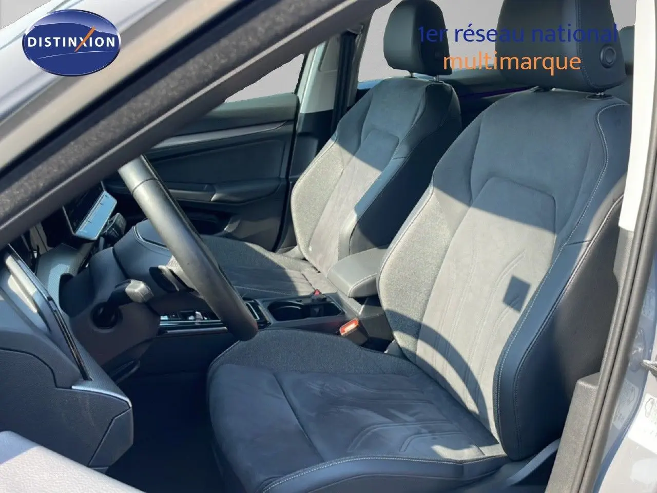 Vue intérieure côté conducteur de la Volkswagen Golf SW VIII gris lunaire, sièges en tissu et cuir gris foncé.