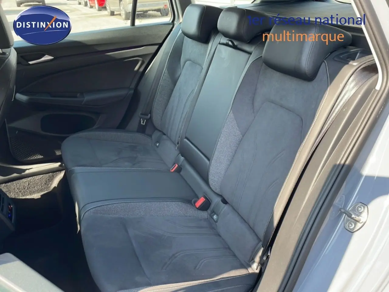 Vue intérieure montrant la banquette arrière en tissu et cuir gris foncé de la Volkswagen Golf SW VIII 2024, porte arrière ouverte.