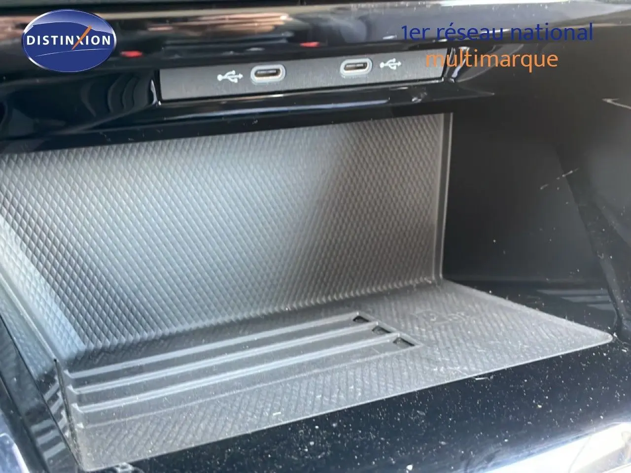 Gros plan sur la console centrale de la Volkswagen Golf SW VIII 2024, montrant les ports USB et un espace de rangement texturé.