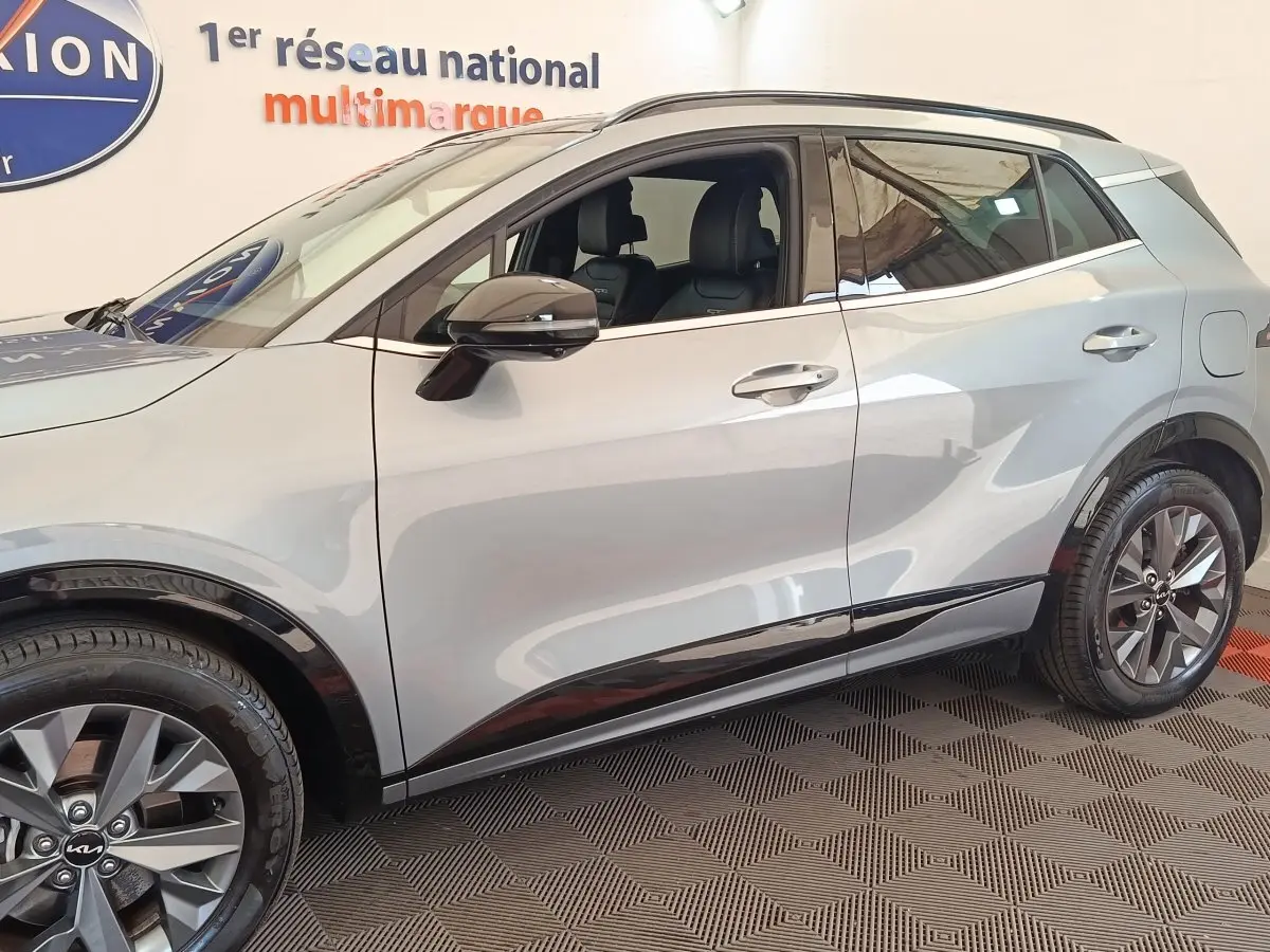 Vue de profil côté gauche du Kia Sportage gris clair 2022 avec jantes alliage et rétroviseurs électriques rabattables.