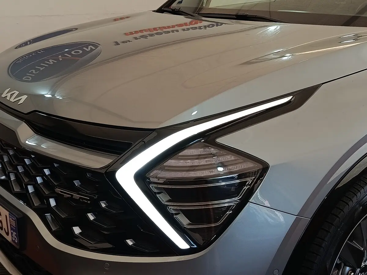 Gros plan sur l’avant droit gris clair du Kia Sportage 2022, avec phares LED en forme de boomerang et calandre noire GT-Line.